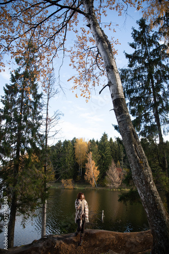 Brunette girl with curls tall with long legs, Golden autumn in the Park by the water, scenic landscape, lake, light brown colored clothes.