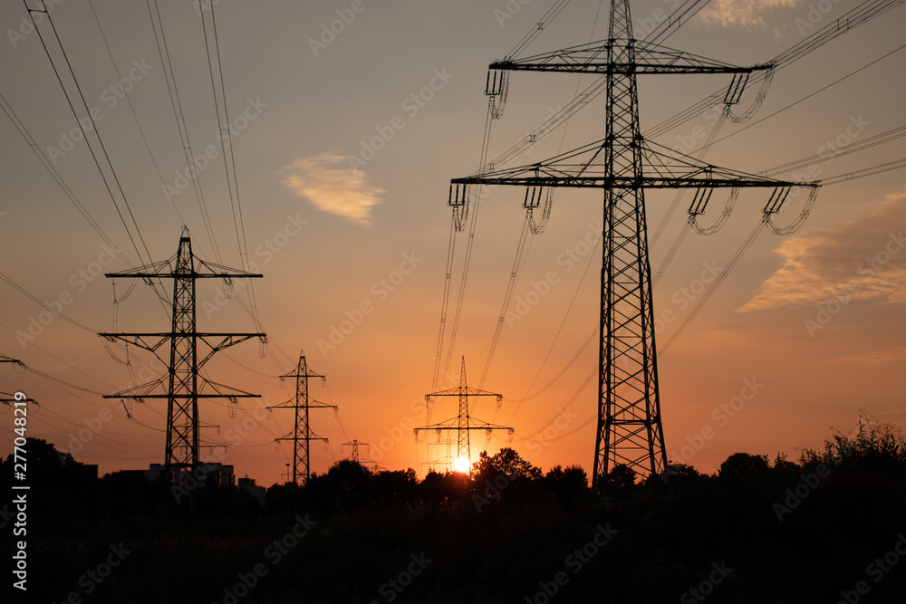 Fototapeta premium Überland Stromleitungen, Hochspannungsmasten im Sonnenuntergang
