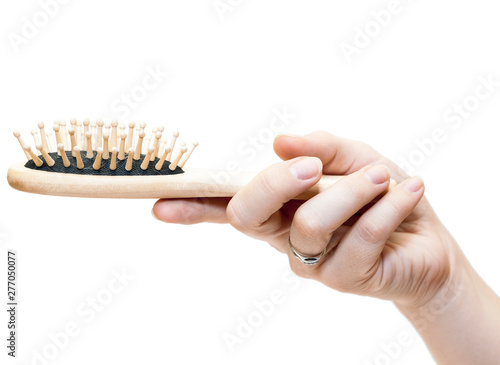 Wooden paddle brush in female hand isolated on white background