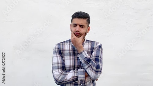 Portrait of confused handsome bearded man in blue checkered shirt standing scratching his head and looking away and thinking with puzzlement face. indoor studio shot isolated on white wall background.