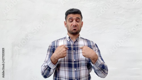 Portrait of proud handsome bearded man in blue checkered shirt standing, pointing and showing himself and looking with haughty confident face. indoor studio shot isolated on white wall background.