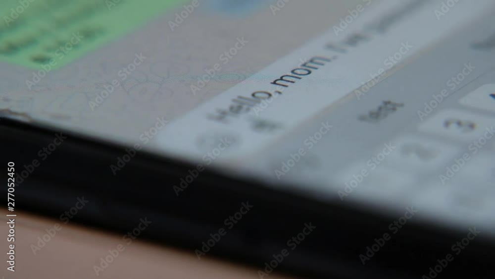 Entering message and texting to his mother on mobile phone, macro shot Entering message and texting to his mother on mobile phone, macro shot