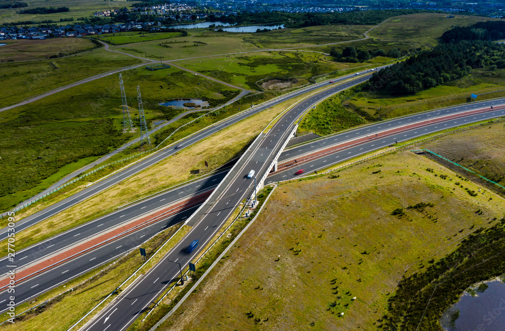 Aerial drone view of a large, new dual carriageway road with motion blurred vehicles (A465, Wales, UK)