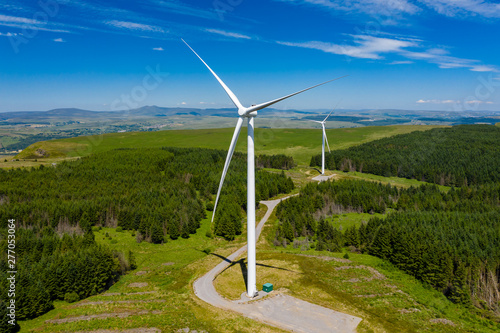 Aerial drone view of turbines at a large onshore windfarm on a green hillside (Pen y Cymoedd, Wales)