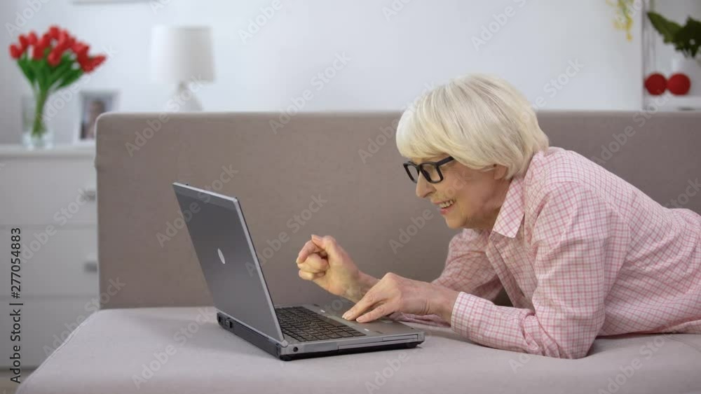Smiling aged woman chatting on laptop with family, studying social networks Smiling aged woman chatting on laptop with family, studying social networks