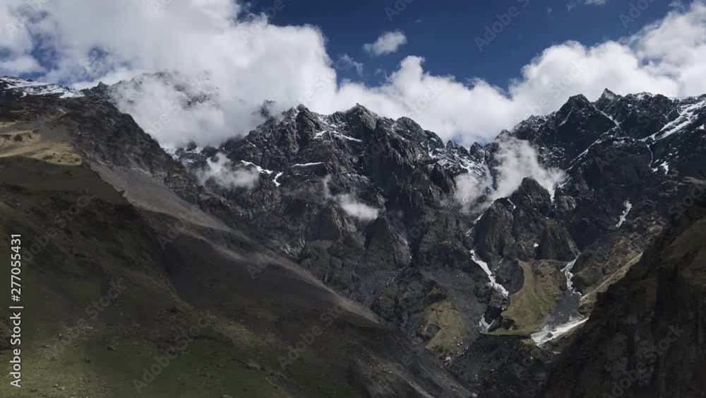 Timelapse of clouds flowing across blue sky over snowy tops of rocky mountains, Georgia, Caucasus. Timelapse of clouds flowing across blue sky over snowy tops of rocky mountains, Georgia, Caucasus.