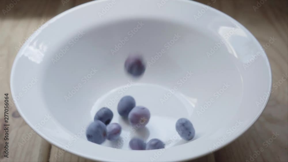 Blueberries falling in white plate, slow motion Blueberries falling in white plate, slow motion