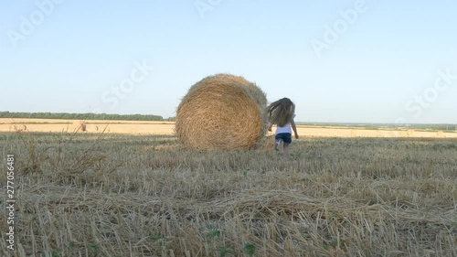 Little girl running to the stacks in the field