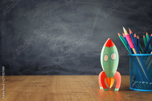 education and back to school concept. cardboard rocket and pencils in front of classroom blackboard
