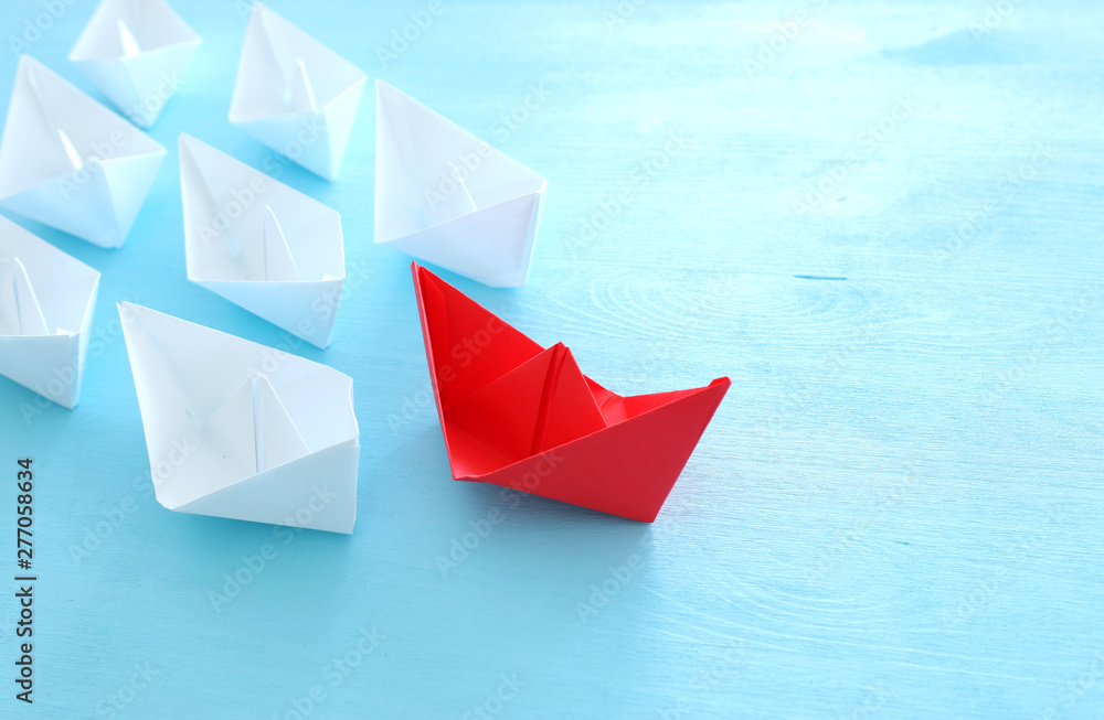 business. Leadership concept image with paper boats on blue wooden background. One leader guiding others. business. Leadership concept image with paper boats on blue wooden background. One leader guiding others.