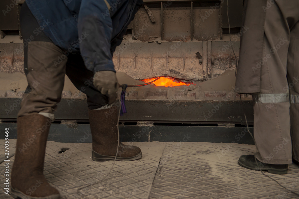man in overalls and protective cap extinguishes flares in anode furnace in aluminum factory. dangerous work. Safe environmental high-tech processes. Modern metallurgical plant. man in overalls and protective cap extinguishes flares in anode furnace in aluminum factory. dangerous work. Safe environmental high-tech processes. Modern metallurgical plant.