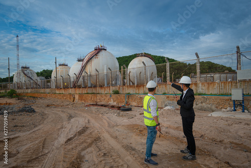 two engineer discussing a new project with large oil refinery background
