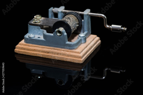 Small hurdy gurdy music box on black shiny reflecting surface close up shot.