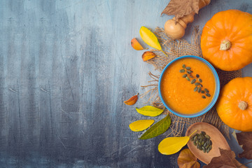 Pumpkin soup on rustic background. Autumn concept with pumpkin and fall leaves. Top view from above