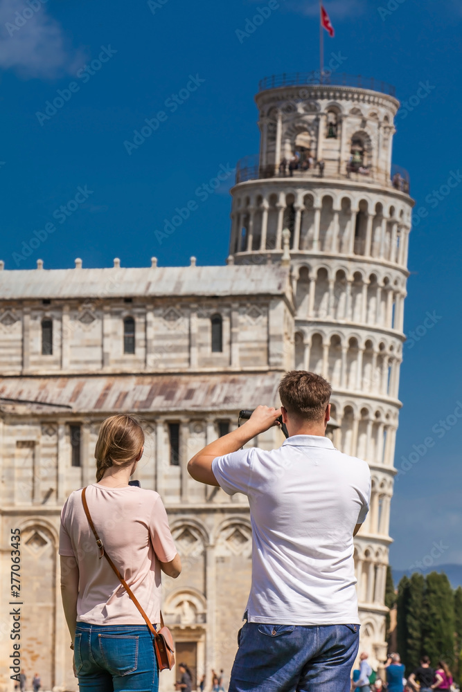 Young couple of tourists taking pictures of the famous Leaning Tower of Pisa