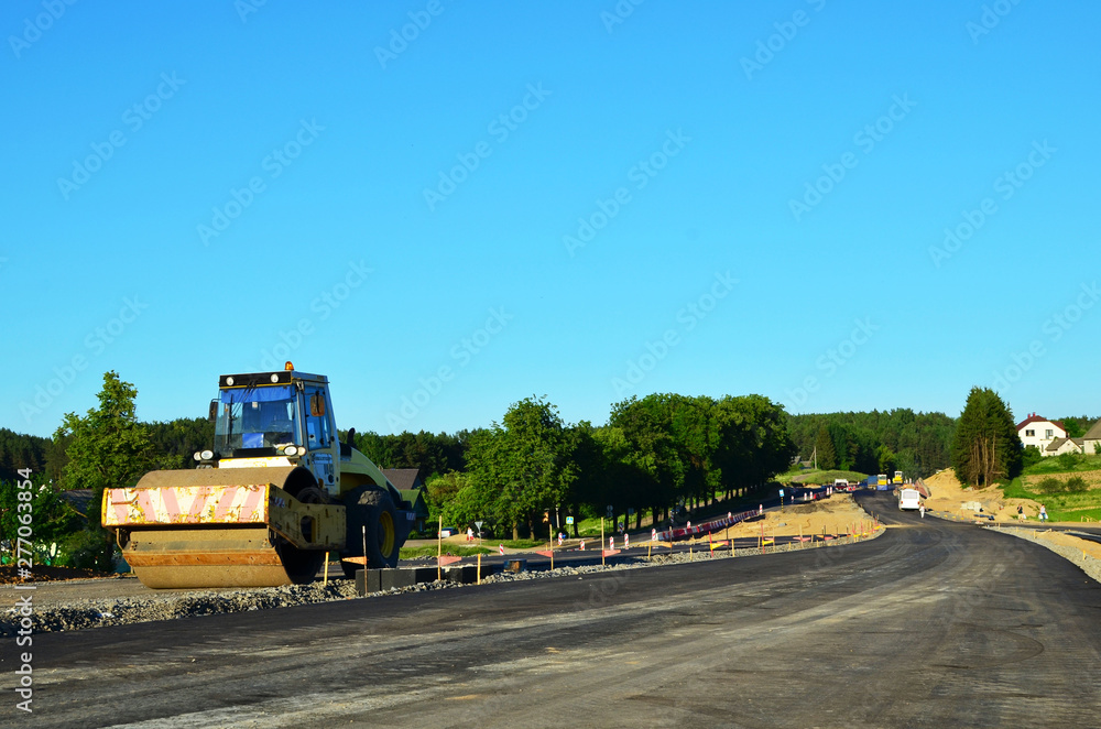 Asphalting construction works with commercial repair equipment. Road rollers leveling fresh asphalt pavement. Road builders are building a new highway, expansion and improvement of the road network