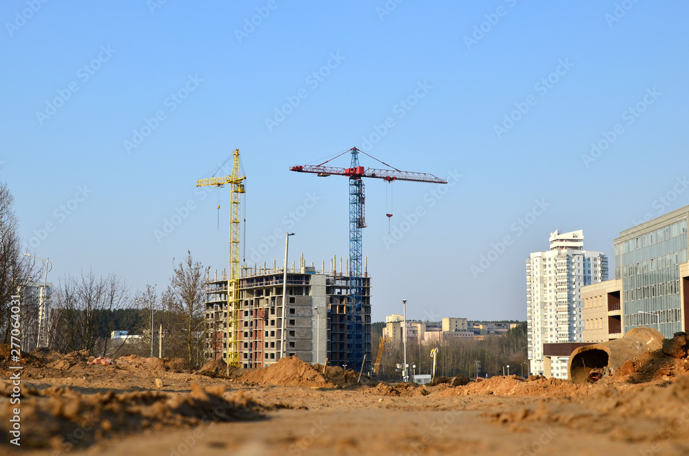 Tower cranes constructing a new building at a construction site. Renovation program, concept of the building industry  - Image