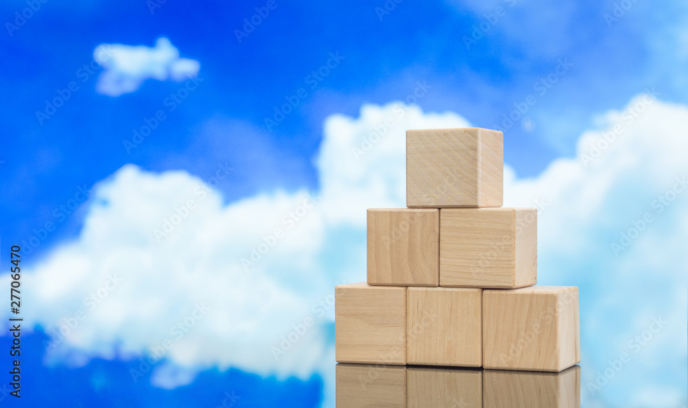 Pyramid of wooden cubes against the blue sky. Wooden cube Stacked in Pyramid shape without graphics for Business and design concept, Symbol of leadership, Teamwork and Growth. Pyramid of wooden cubes against the blue sky. Wooden cube Stacked in Pyramid shape without graphics for Business and design concept, Symbol of leadership, Teamwork and Growth.