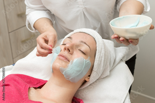 Face skin care. Beautician applying beauty oil mask on face using brush In spa salon	