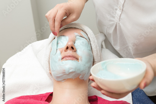 Face skin care. Beautician applying beauty oil mask on face using brush In spa salon 