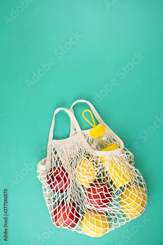 Reusable shopping mesh bag with lemons, fruits and glass bottle