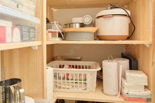 Wooden shelves with food and utensils, kitchen appliances in the pantry photo