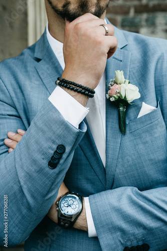 Closeup of stylish groom in a suit with boutonniere.