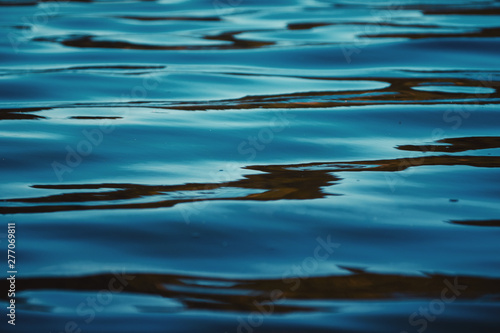 Close up water ripples with a lot of contrast of calm blue lake water. Liquid water texture. National Park Harz in Germany