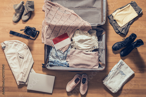 Woman's clothes, laptop, camer, russian passport and flag of Indonesia lying on the parquet floor near and in the open suitcase. Travel concept
