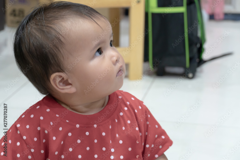 Φωτογραφία Asian baby girl in red shirt is looking up