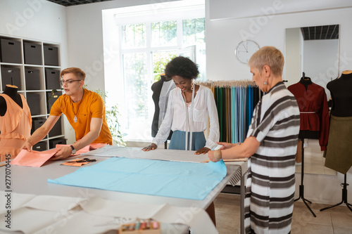Motivated modern fashion designers preparing for cutting fabric