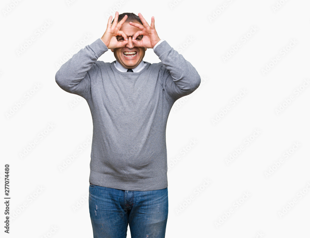 Middle age bussines arab man wearing glasses over isolated background doing ok gesture like binoculars sticking tongue out, eyes looking through fingers. Crazy expression.