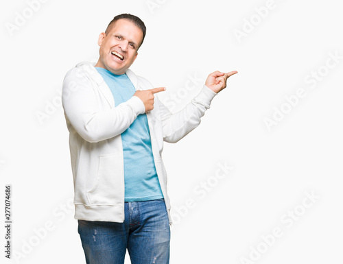 Middle age arab man wearing sweatshirt over isolated background amazed and smiling to the camera while presenting with hand and pointing with finger.