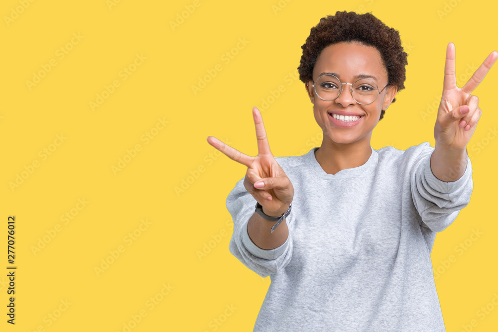 Young beautiful african american woman wearing glasses over isolated background smiling looking to the camera showing fingers doing victory sign. Number two. Young beautiful african american woman wearing glasses over isolated background smiling looking to the camera showing fingers doing victory sign. Number two.
