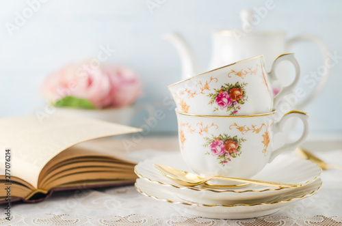 Cup of tea with book, teapot and rose flowers on blue background with vintage tone - Afternoon tea party concept