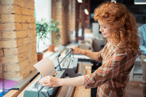 Curly beautiful woman smiling while printing documents