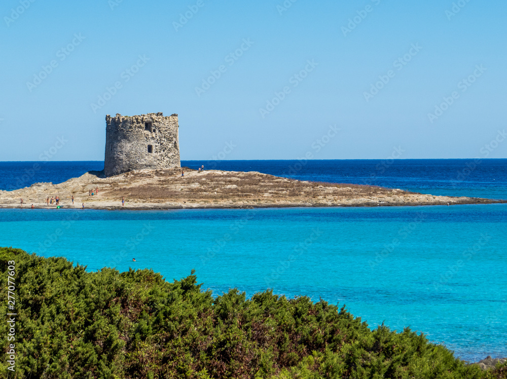 La Pelosa Beach in Stintino, Sardinia, Italy. In the background, the landmark 16th century La Pelosa Tower (Italian: Torre della Pelosa).