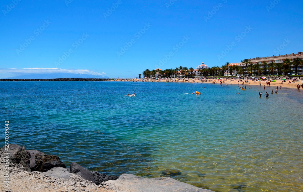 Fototapeta premium View of Playa del Camison beach with turquoise water and yellow sand in Las Americas, Tenerife,Canary Islands, Spain.Summer vacation or travel concept