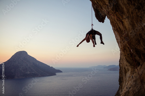 Young female rock climber hanging on rope while being lowered down