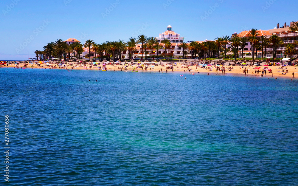 View of Playa del Camison beach with turquoise water and yellow sand in Las Americas, Tenerife,Canary Islands, Spain.Summer vacation or travel concept View of Playa del Camison beach with turquoise water and yellow sand in Las Americas, Tenerife,Canary Islands, Spain.Summer vacation or travel concept