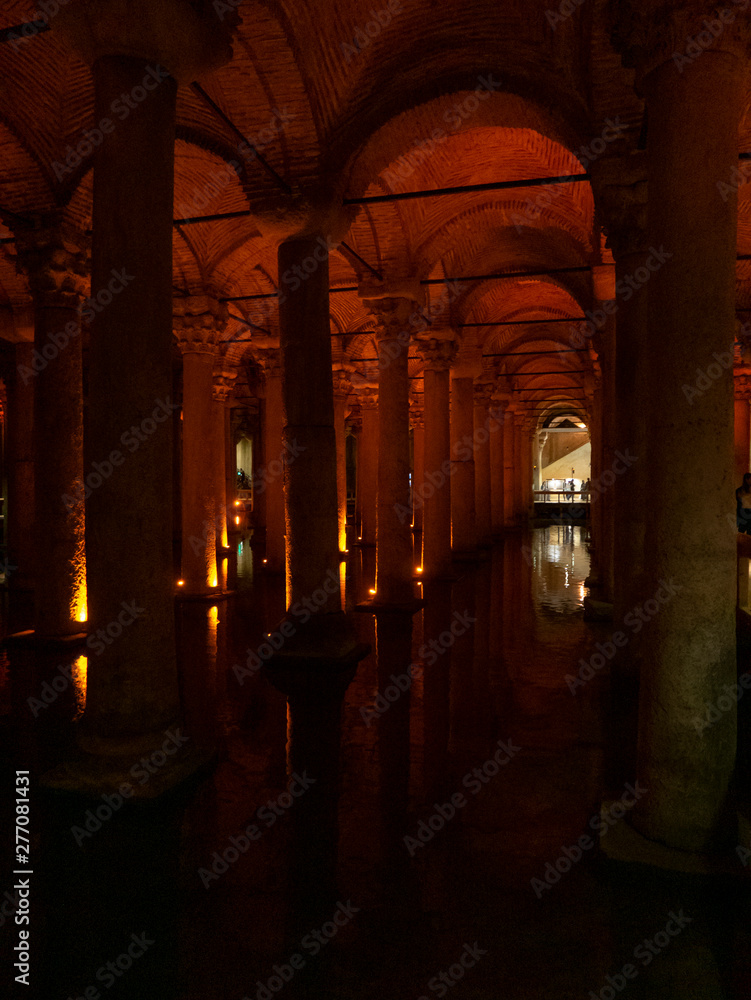 Interior of Basilica Cistern illuminated with orange colored lights.