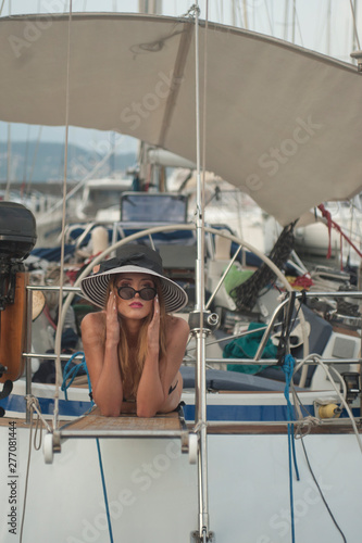 Ragazza sdraiata su passerella di imbarco yacht ancorato in porto turistico photo