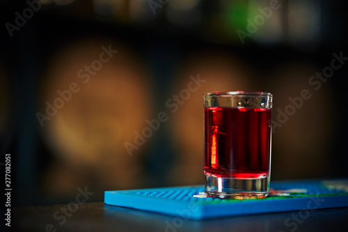 shot with a red drink on the background of a bar with oak barrels