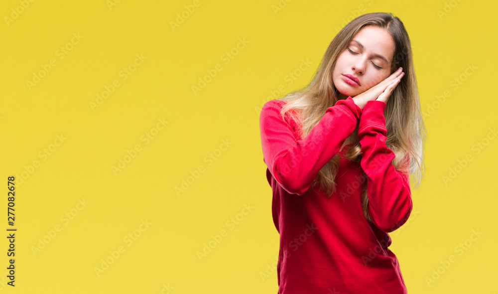 Young beautiful blonde woman wearing red sweater over isolated background sleeping tired dreaming and posing with hands together while smiling with closed eyes. Young beautiful blonde woman wearing red sweater over isolated background sleeping tired dreaming and posing with hands together while smiling with closed eyes.