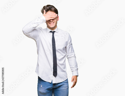 Young business man wearing glasses over isolated background smiling and laughing with hand on face covering eyes for surprise. Blind concept.