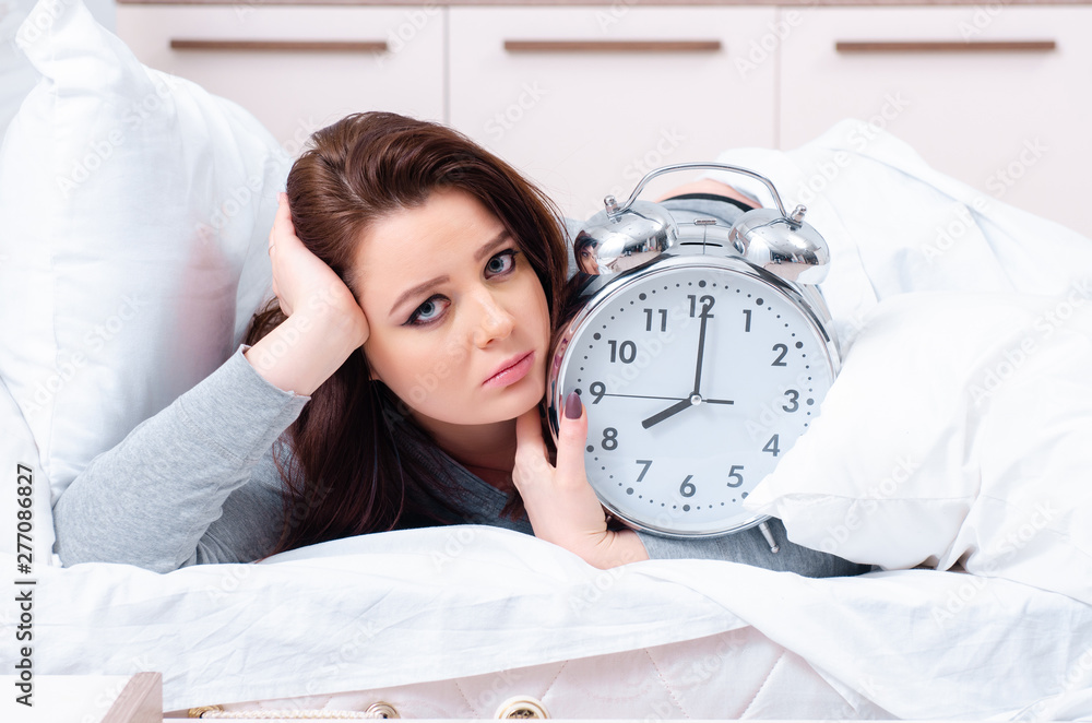 Young woman lying on the bed in time management concept Young woman lying on the bed in time management concept