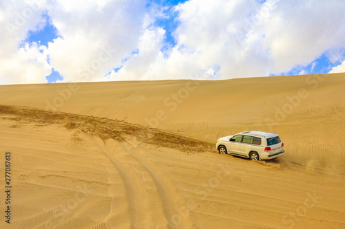Off-road adventure with SUV in Arabian Desert. 4x4 vehicle bashing through sand dunes at Khor Al Udeid, the inland sea near Qatar and Saudi Arabian, Persian Gulf, Middle East.