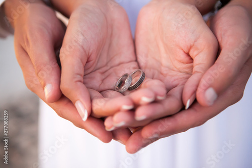 Bride and groom holding wedding rings on their palms during ceremony