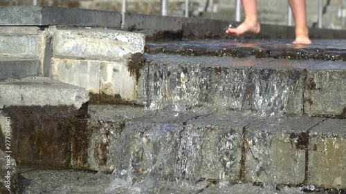 Barefoot legs play with fountain water jets. People in town play with water in the fountains, happy and carefree, concept of freedom and happiness in childhood, starting summer and tourist cities.