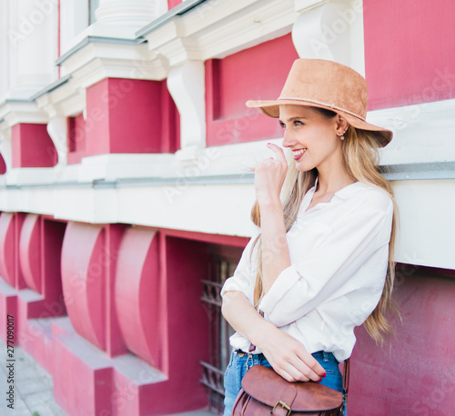 Beauty casual style woman in felt hat posing against the background of old urban architecture. Street fashion